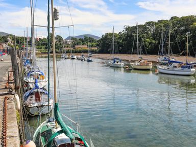 A river with sailboats moored along the edge and trees in the background at Tyddyn Parthle Pod 1 in Bontnewydd Gwynedd
