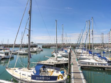 A marina with sailboats docked along piers under a clear blue sky