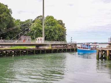 A blue boat near a drawbridge over water with trees and a small building in the background at Tyddyn Parthle Pod 1 Bontnewydd Gwynedd