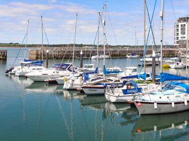 Sailboats moored in a marina with a stone wall and buildings in the background at Tyddyn Parthle Pod 1 Bontnewydd Gwynedd