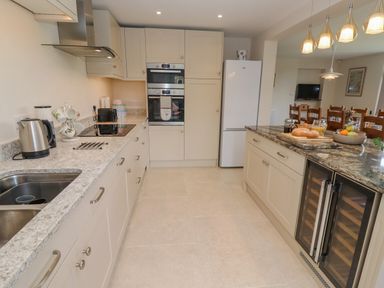 A kitchen with countertops cabinets a sink refrigerator oven and dining area at The Gables in Sheepscombe