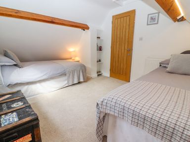 A bedroom with two single beds a wooden door and a black vintage trunk at The Gables in Sheepscombe