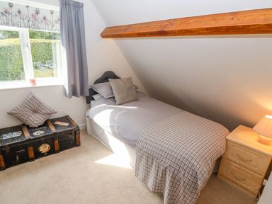 A bedroom with a single bed pillow chest bedside table and lamp at The Gables in Sheepscombe