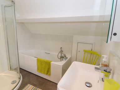 A bathroom with a bathtub a shower a sink and a chair at The Gables in Sheepscombe