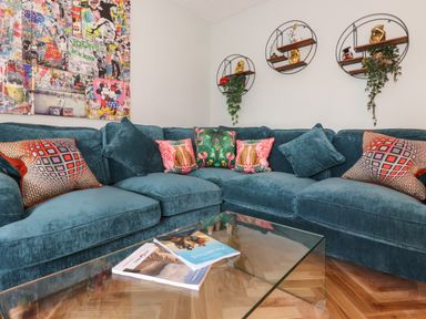 A corner sofa with colorful cushions and a glass coffee table with magazines in a living room