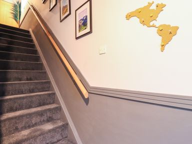 A carpeted staircase with wooden handrail and framed pictures on the wall at Tipsy Bee in Bowness-On-Windermere