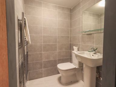 A bathroom with a toilet pedestal sink and towel rack at Tipsy Bee in Bowness-On-Windermere