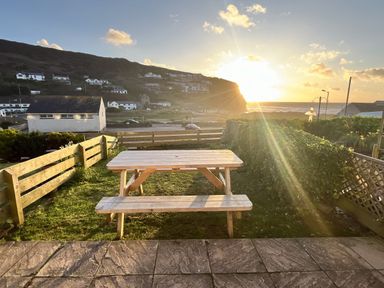 An outdoor area with a table and bench overlooking the sea at Kippy Cottage in Truro