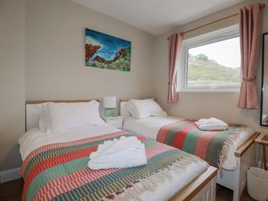 A bedroom with two beds and a window at Kippy Cottage Porthtowan