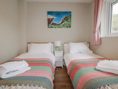 A bedroom with two single beds and a painting at Kippy Cottage in Porthtowan