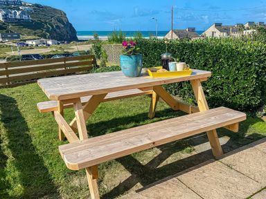 A table with benches and a plant pot at Kippy Cottage in Porthtowan