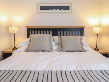 A bedroom with a bed that has two pillows and two lamps on bedside tables at Glynside in Conwy