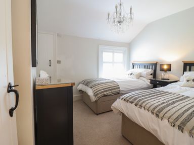A bedroom with two single beds a small bedside table with a lamp and a chest of drawers at Glynside in Conwy