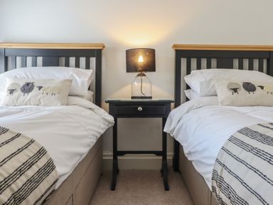 A bedroom with two single beds a bedside table and a lamp at Glynside in Conwy