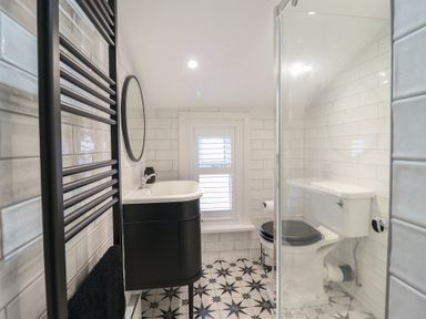 A bathroom with a black towel rack sink with mirror toilet and patterned floor at Glynside in Conwy