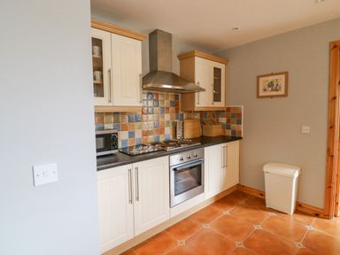 A kitchen with cream cabinets a stainless steel oven and stove a microwave and a white trash bin at 14 Sneem Leisure Village in Sneem County Kerry