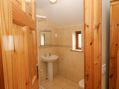 A bathroom with a pedestal sink a mirror a window and a wooden door at 14 Sneem Leisure Village in Sneem County Kerry