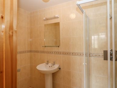A bathroom with a pedestal sink mirror above and a glass shower enclosure at 14 Sneem Leisure Village in Sneem County Kerry