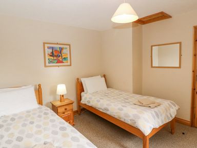 A bedroom with two single beds a bedside table with a lamp a wall mirror and a framed picture at 14 Sneem Leisure Village in Sneem County Kerry