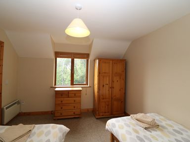 A bedroom with two single beds a wooden wardrobe a wooden chest of drawers and a window at 14 Sneem Leisure Village in Sneem County Kerry