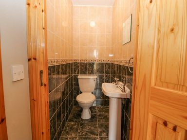 A bathroom with a toilet and a sink with tiled walls and floor at 14 Sneem Leisure Village in Sneem County Kerry