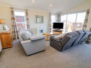 A living room with sofas coffee table television and sliding glass doors at Gressingham 22 in South Lakeland Leisure Village