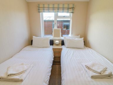 A bedroom with two single beds separated by a nightstand under a window at Gressingham 22 in South Lakeland Leisure Village