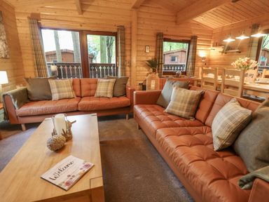 A living room with two brown leather sofas and a wooden coffee table at Leafy Hollow Lodge in Louth
