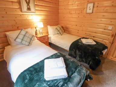 A bedroom with two single beds a nightstand with a lamp and rabbit figurine in Leafy Hollow Lodge in Louth