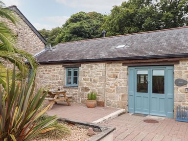 An outdoor area with a stone building with blue doors and window at Pendeen in Mawnan Smith Near Falmouth