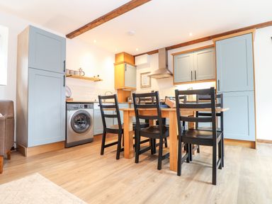 A kitchen with wooden table and black chairs and grey cabinets at Pendeen in Mawnan Smith Near Falmouth