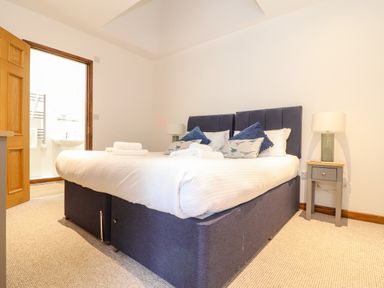 A bedroom with a large bed pillows bedside tables and lamps at Pendeen in Mawnan Smith Near Falmouth