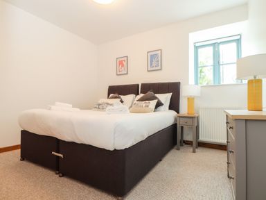 A bedroom with a double bed two bedside tables lamps a chest of drawers and a window at Pendeen in Mawnan Smith Near Falmouth