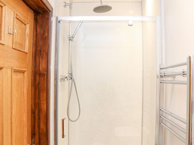 A shower with a glass door wooden door on the left and a towel rack on the right at Pendeen in Mawnan Smith Near Falmouth