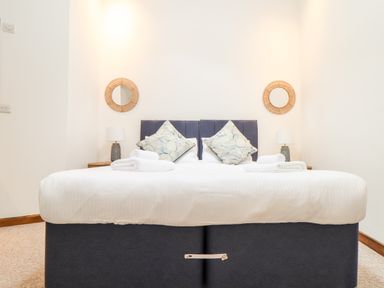A bedroom with a bed with white sheets and two pillows with two towels on top at Pendeen in Mawnan Smith Near Falmouth