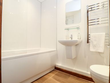 A bathroom with a bathtub a sink a mirror a towel rack with a towel and a toilet at Pendeen in Mawnan Smith Near Falmouth