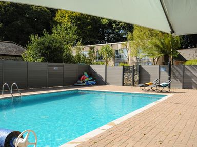 An outdoor swimming pool with two lounge chairs and inflatable pool toys at Pendeen in Mawnan Smith Near Falmouth