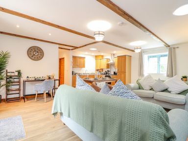 An open plan living room with sofas and cushions dining table and kitchen cabinets at Budock in Mawnan Smith Near Falmouth