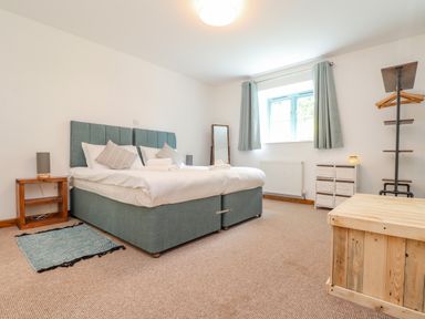 A bedroom with a double bed bedside tables a window a standing mirror and a wooden chest at Budock in Mawnan Smith Near Falmouth