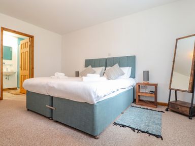 A bedroom with a double bed bedside table with a lamp and a full-length mirror at Budock in Mawnan Smith Near Falmouth