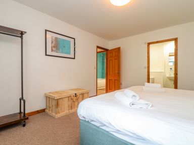 A bedroom with a bed and rolled towels a wooden chest and a framed picture on the wall at Budock in Mawnan Smith Near Falmouth