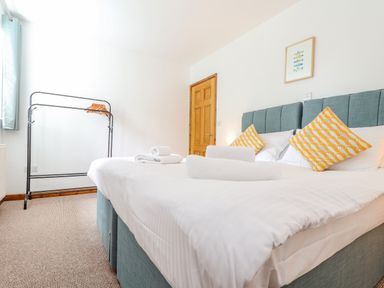 A bedroom with a double bed with blue headboards and yellow patterned pillows at Budock in Mawnan Smith Near Falmouth