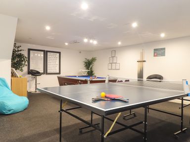 An indoor game room with a ping pong table and pool table along with chairs and wall decorations at Kerensa in Mawnan Smith Near Falmouth