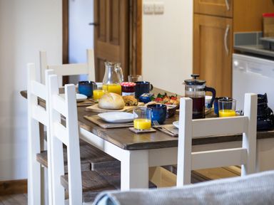 A dining table with white chairs set with bread jam orange juice and coffee in a kitchen at Kerensa in Mawnan Smith Near Falmouth