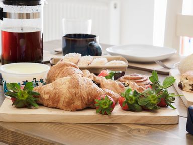 A wooden table with croissants strawberries a tub of spread a French press coffee pot and pastries at Kerensa in Mawnan Smith Near Falmouth
