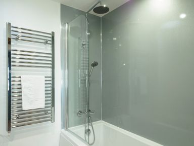 A bathroom with a bathtub shower combination and a towel rail at Kerensa in Mawnan Smith Near Falmouth