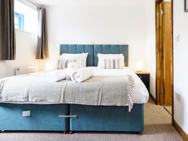 A bedroom with a bed with rolled towels pillows and bedside lamps at Kerensa in Mawnan Smith Near Falmouth