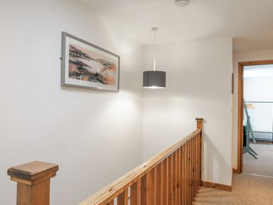 A hallway with wooden railing a hanging light fixture and a framed painting at Newlyn in Mawnan Smith Near Falmouth