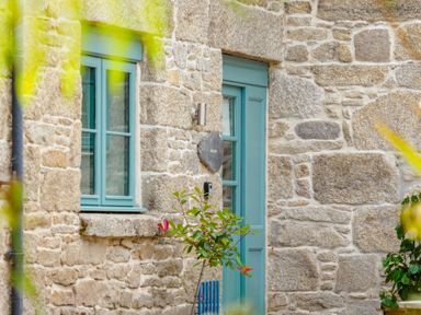 A stone building with a blue door and window with plants in front at Newlyn in Mawnan Smith Near Falmouth