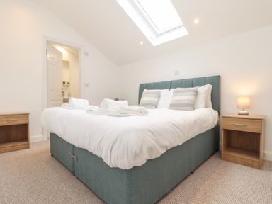 A bedroom with a double bed bedside tables towels and a skylight window at Penpoll in Falmouth